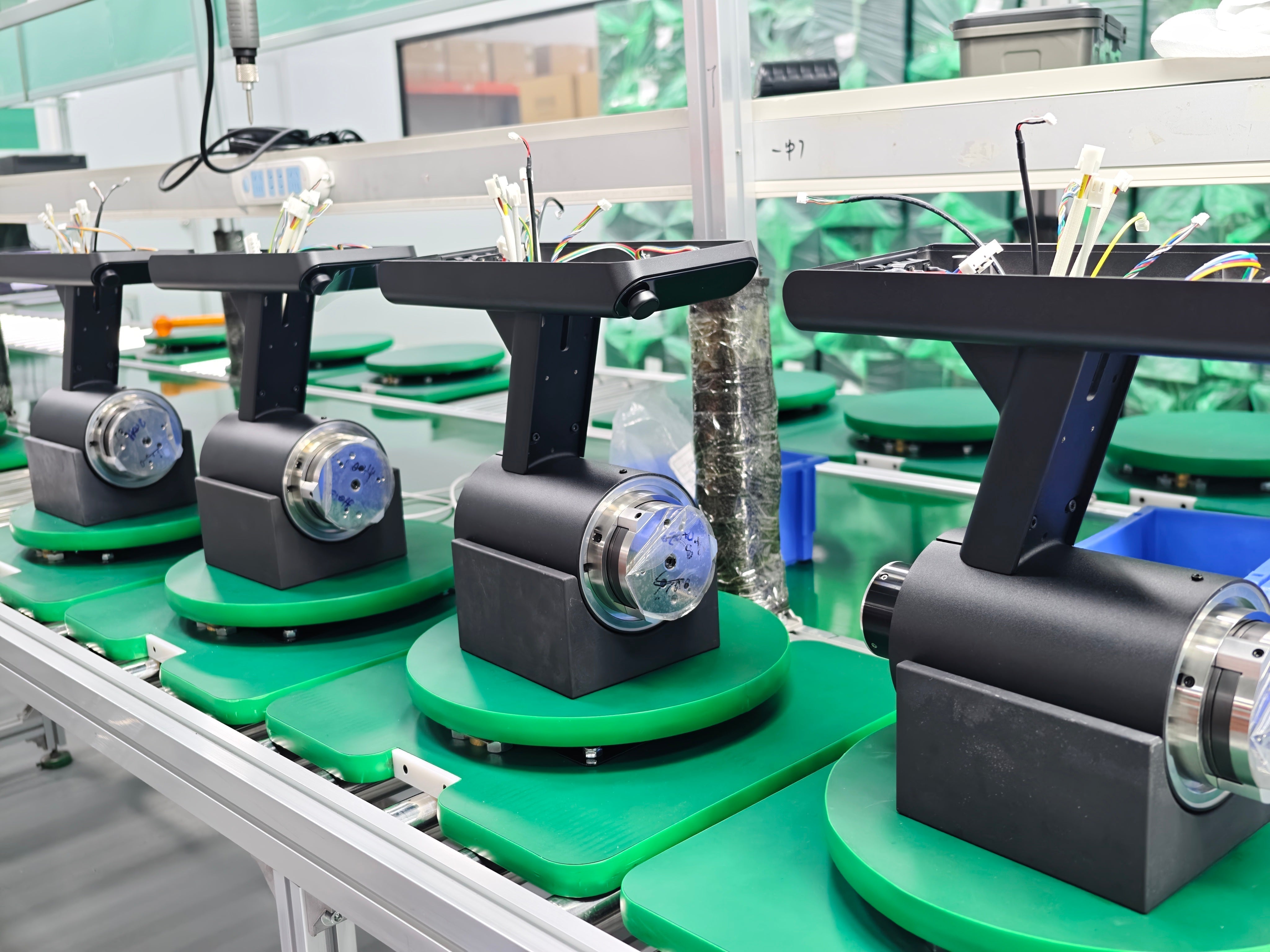 Partially assembled Motto 80 grinders on production fixtures during firmware flashing and calibration.